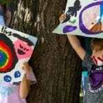 Children hold colorful Black Lives Matter signs in a peaceful outdoor protest.