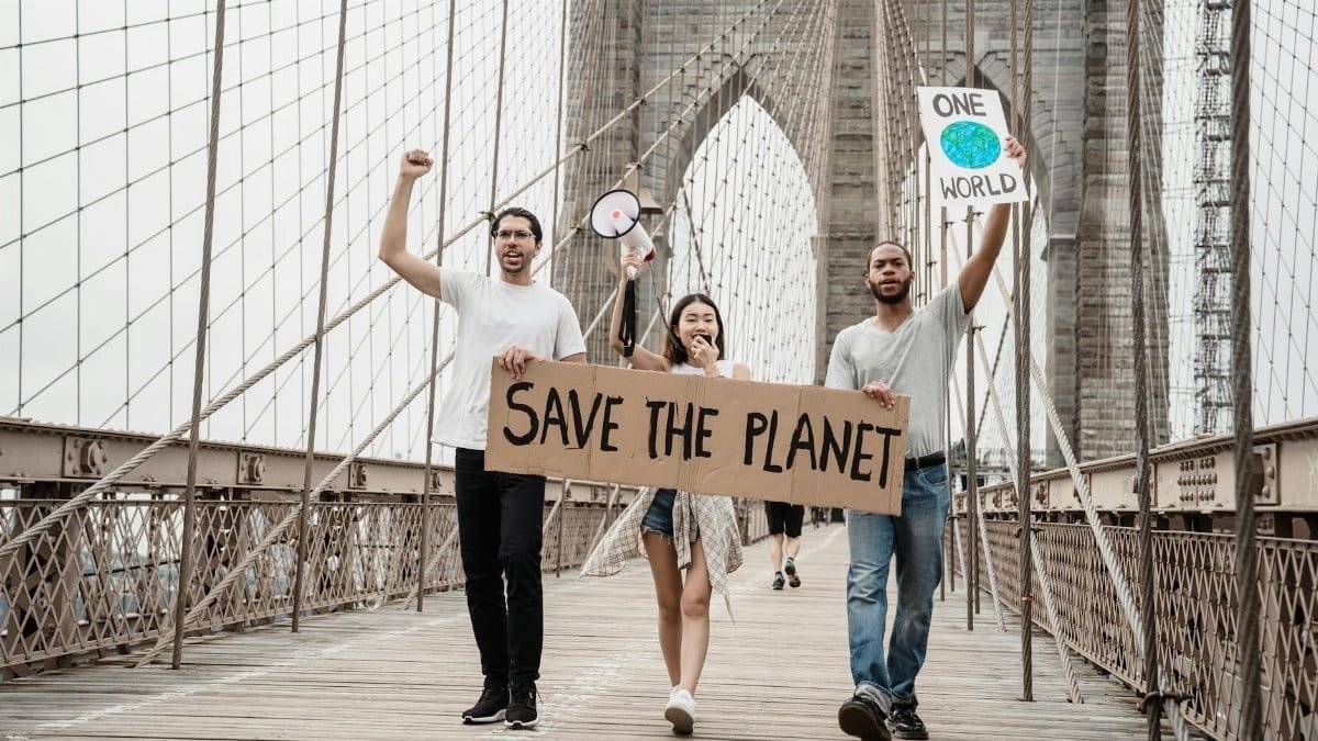 Group of young activists holding signs on Brooklyn Bridge for environmental protest.