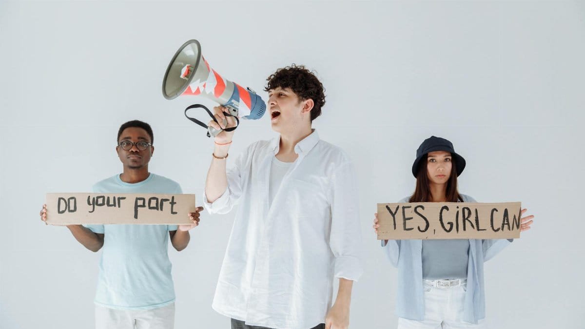 A diverse group of young adults protesting with signs and a megaphone, promoting activism and social change.