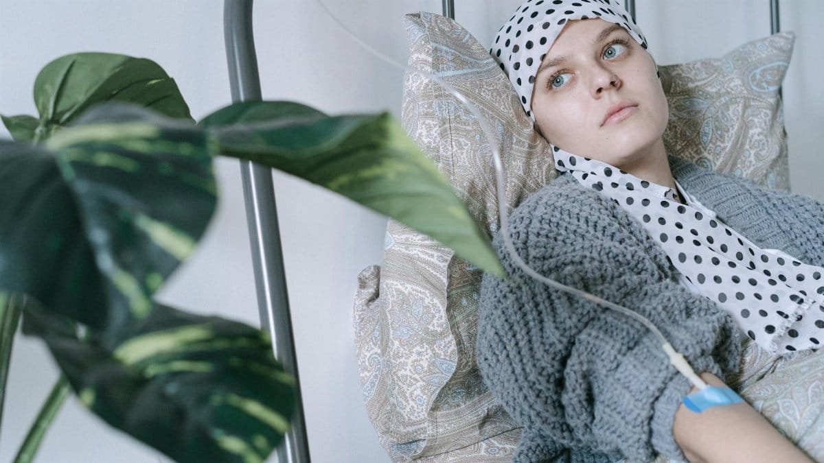 Young woman in hospital bed receiving cancer treatment, reflecting resilience.