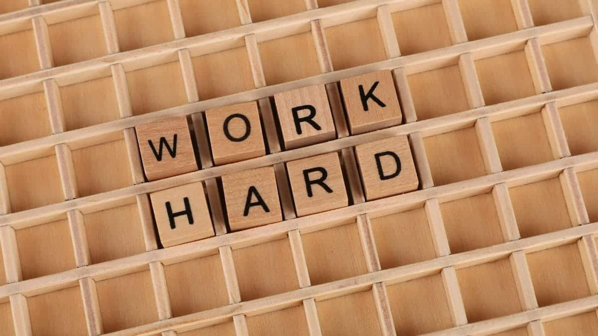 Creative wooden letter tiles forming the phrase 'work hard' on a grid. Perfect for motivation themes.