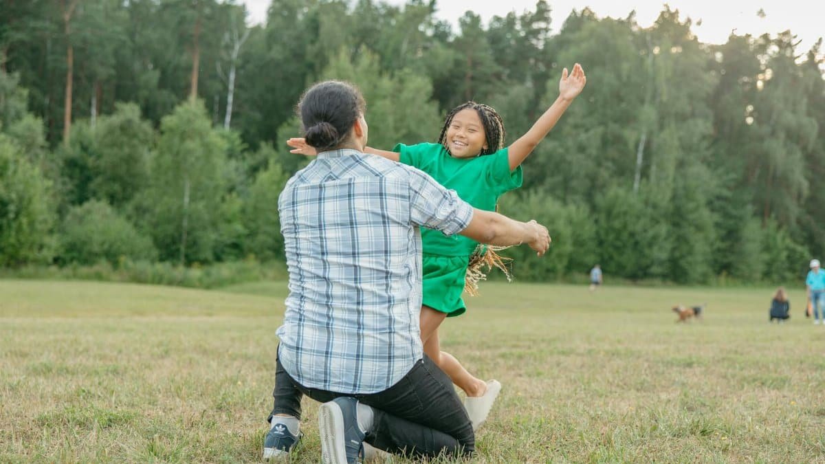 A happy moment of a father embracing his daughter in a lush park setting.
