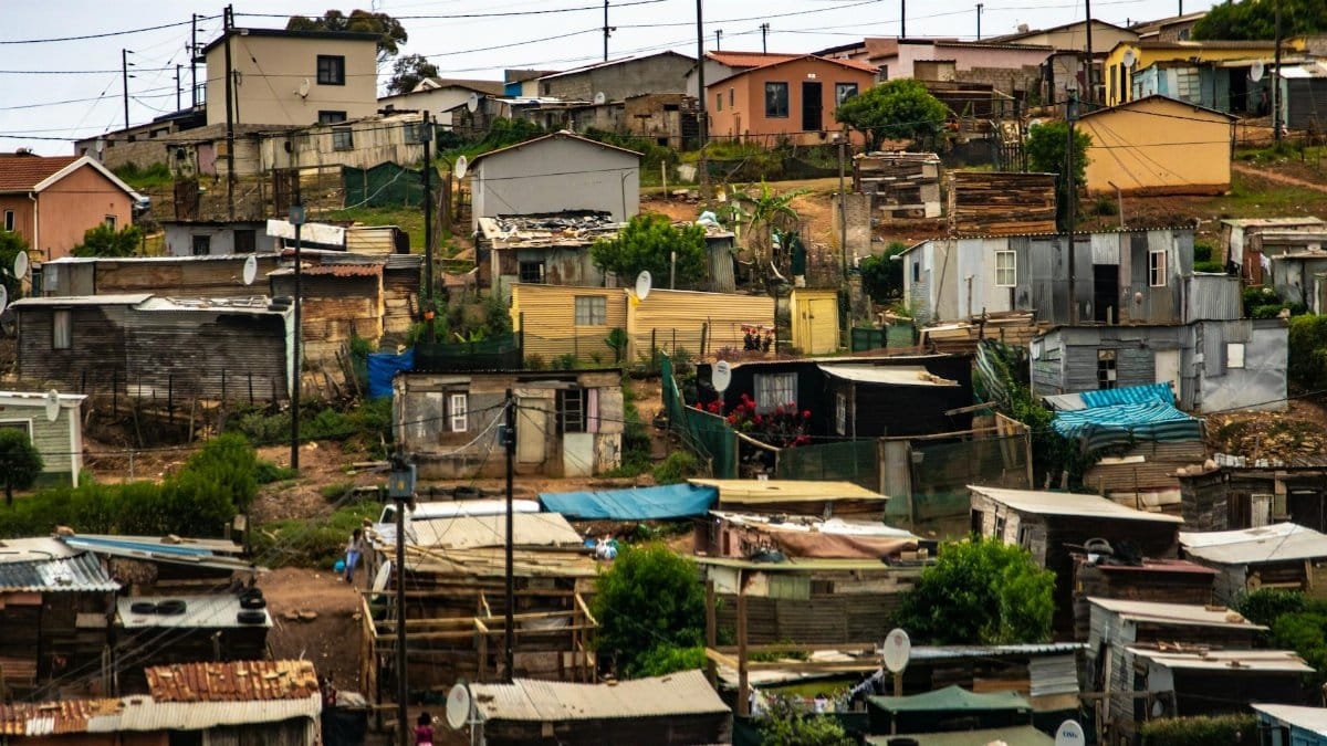 Colorful view of a shantytown with various houses and electric poles under an overcast sky.