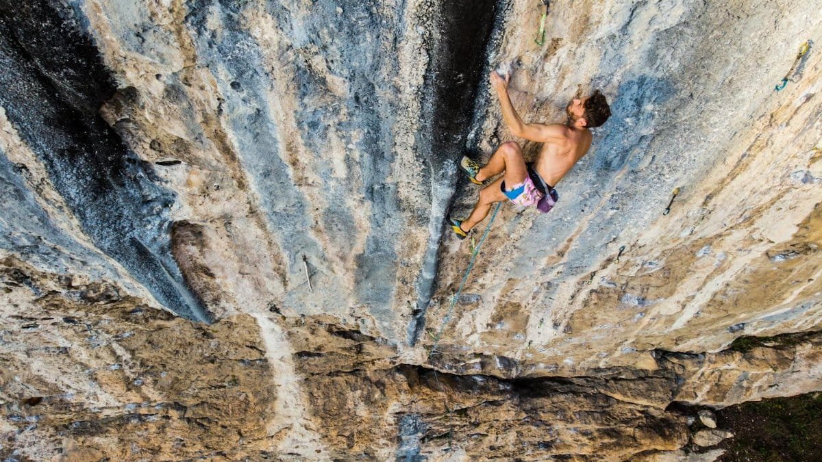 A rock climber demonstrates skill and bravery scaling a steep limestone wall in Italy.
