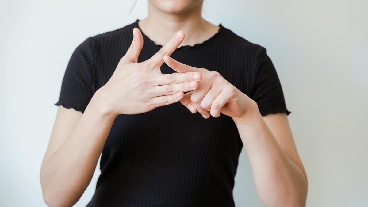 A woman making sign language gestures in a close-up shot indoors.