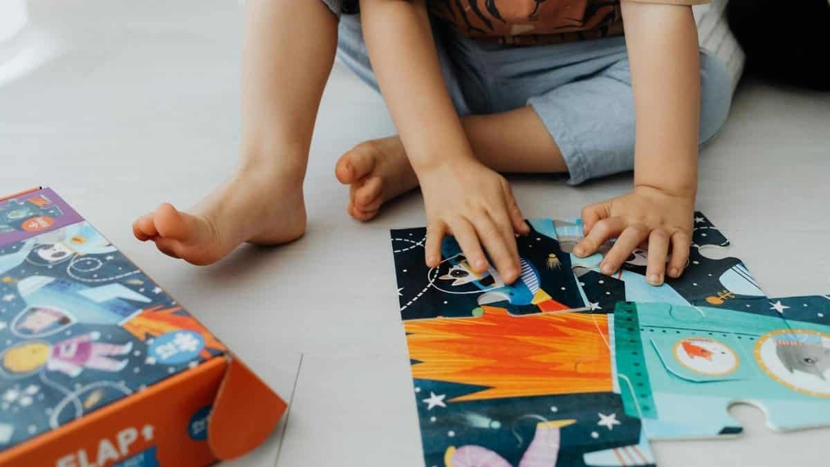 Children working together to solve a colorful space-themed puzzle indoors.