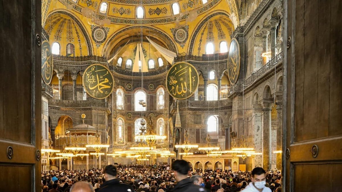 A bustling crowd inside a historic Istanbul mosque, showcasing Islamic architecture and spiritual ambiance.