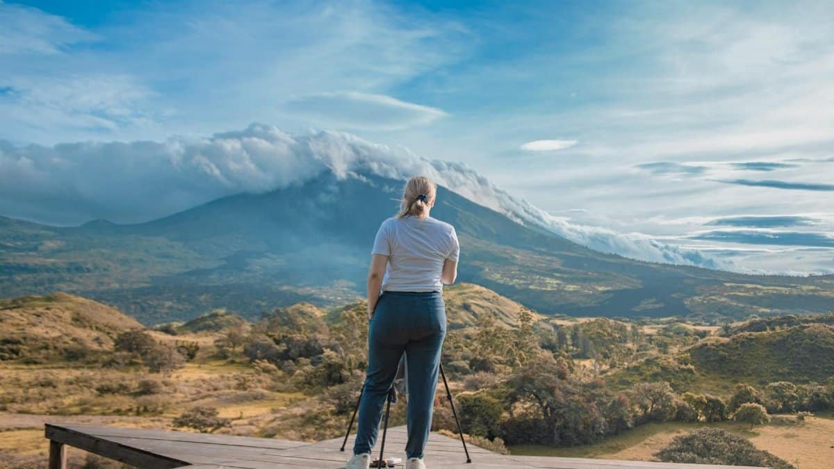 Woman standing on platform capturing stunning volcano landscape in Los Pocitos, Guatemala.