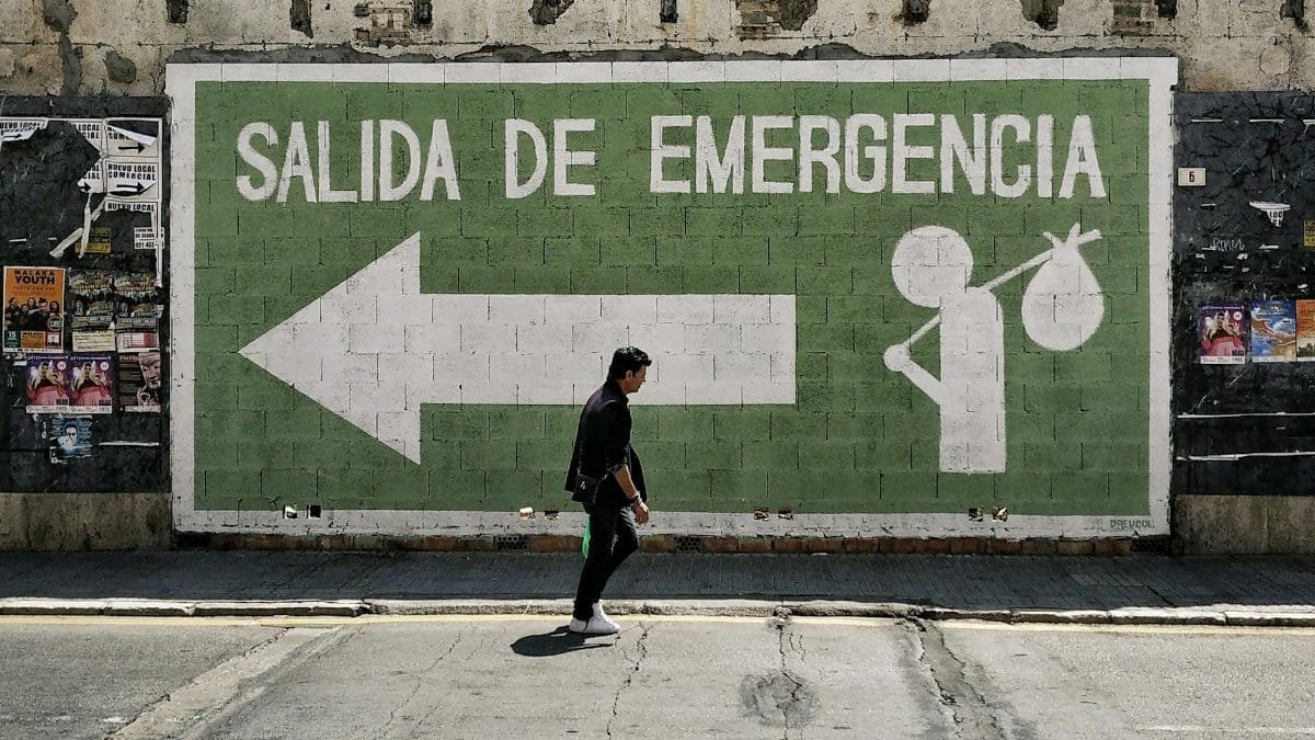 A man walks by an emergency exit graffiti mural on a street in Málaga, Spain.