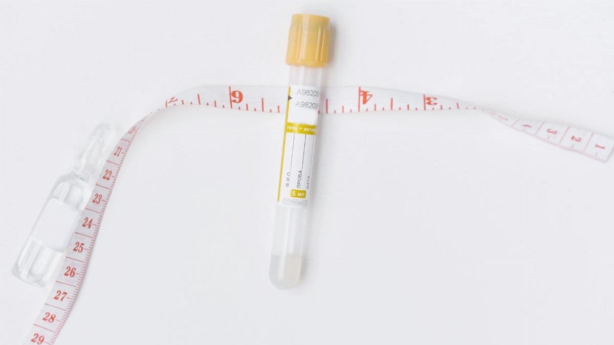Image of an empty test tube and a measuring tape on a white background, ideal for healthcare and laboratory themes.