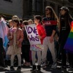 Celebrate diversity with a vibrant Pride parade featuring a Love Wins sign and rainbow flag in Riga, Latvia.