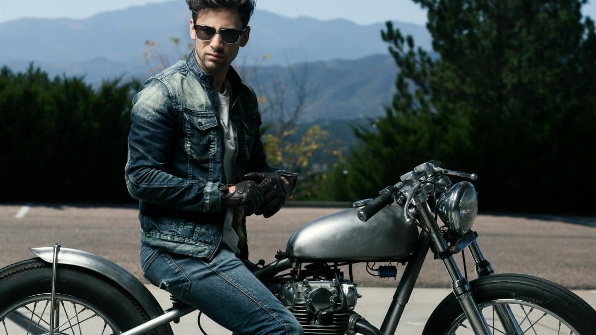 Man on a vintage motorcycle in Colorado Springs with mountains in the background.