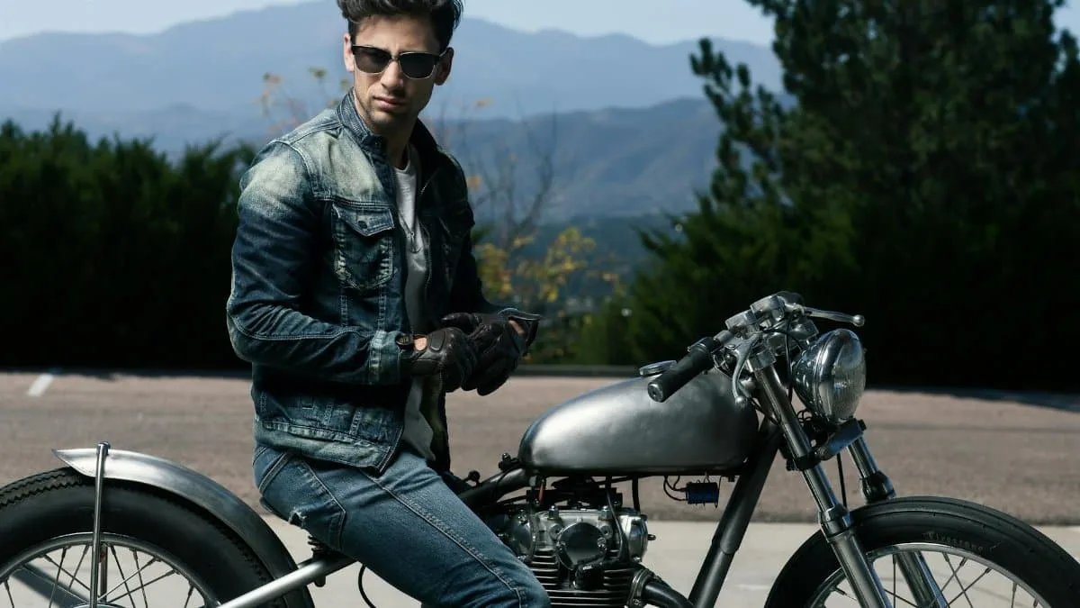 Man on a vintage motorcycle in Colorado Springs with mountains in the background.