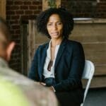 A therapist leads a group therapy session with military veterans in an indoor setting.