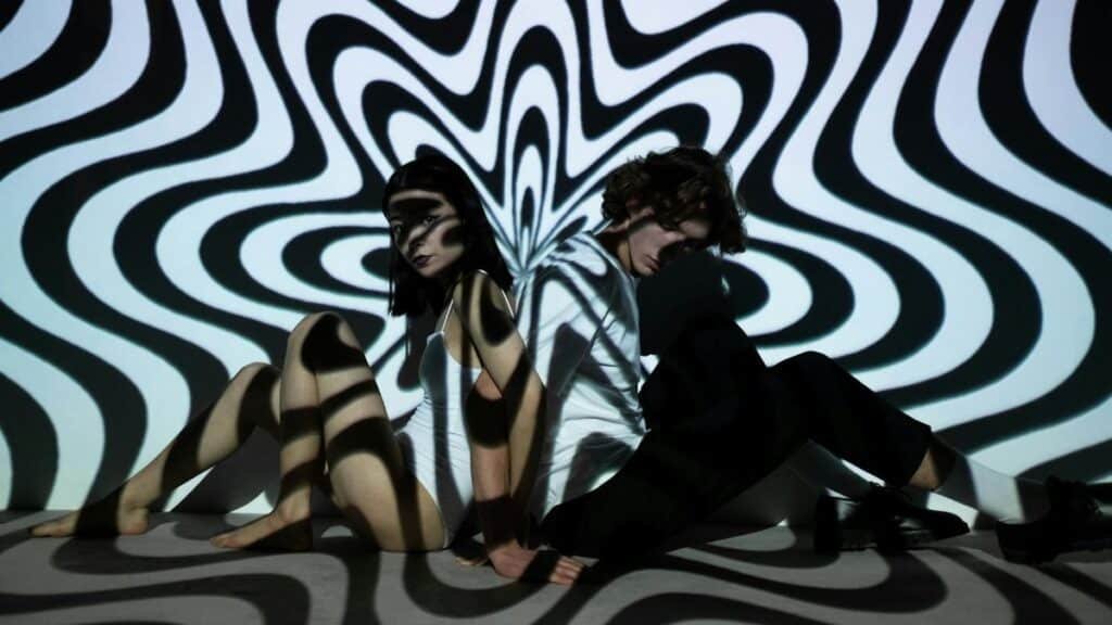 A vibrant double exposure featuring a man and woman with captivating optical illusions and abstract patterns.