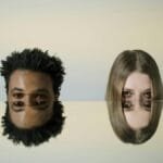 Two faces mirrored on a smooth surface creating a dual reflection effect.