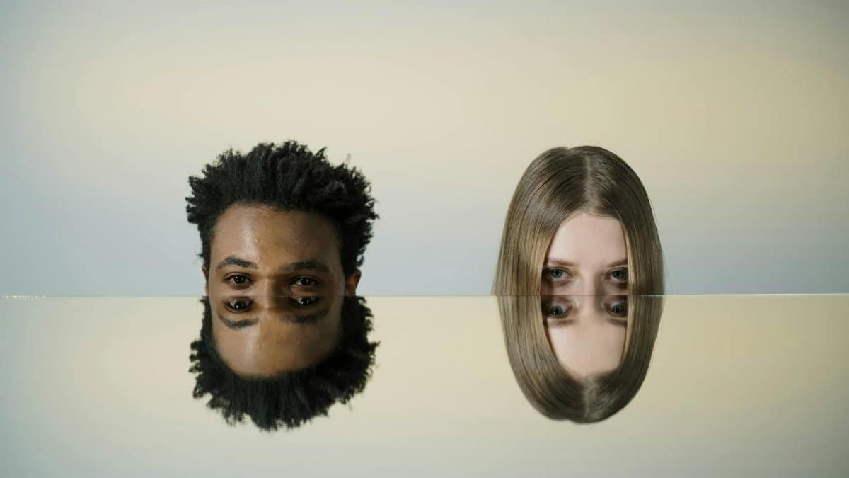 Two faces mirrored on a smooth surface creating a dual reflection effect.