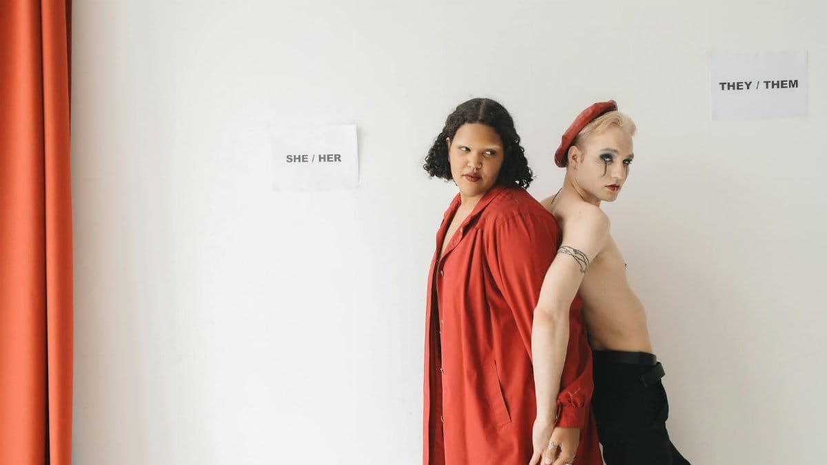 Two individuals expressing gender diversity with unique fashion choices against a neutral background.