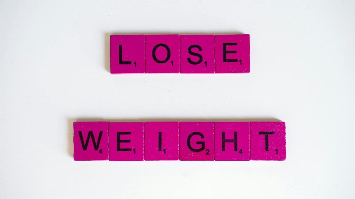 Creative image of the phrase 'Lose Weight' spelled with Scrabble tiles on a white background.