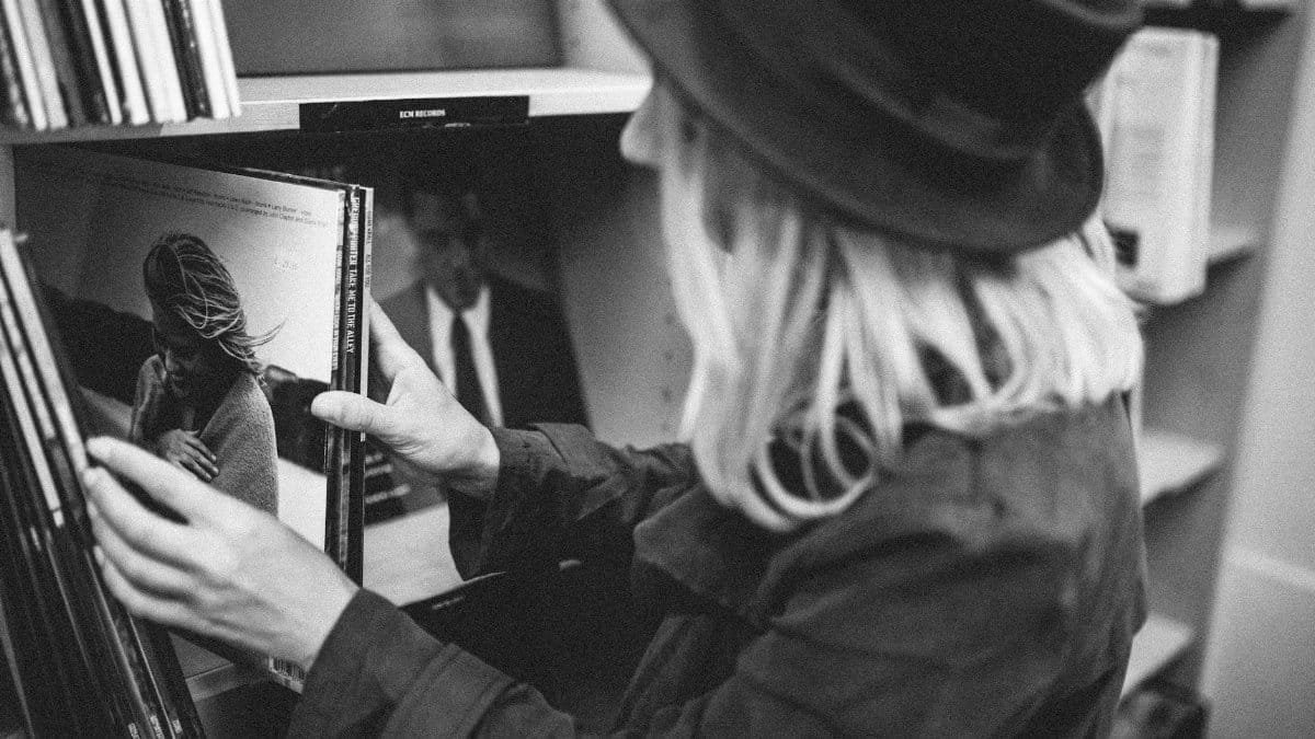 Woman browsing vinyl records in a classic black and white setting.