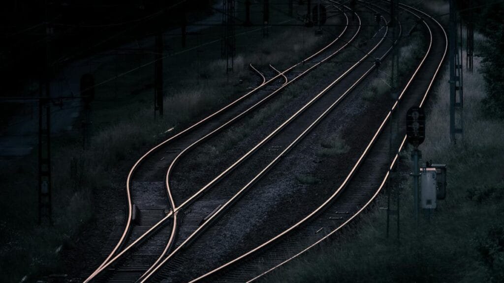 Aerial view of railway tracks at night in a remote, rural area, capturing a dark and moody ambiance.