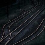 Aerial view of railway tracks at night in a remote, rural area, capturing a dark and moody ambiance.