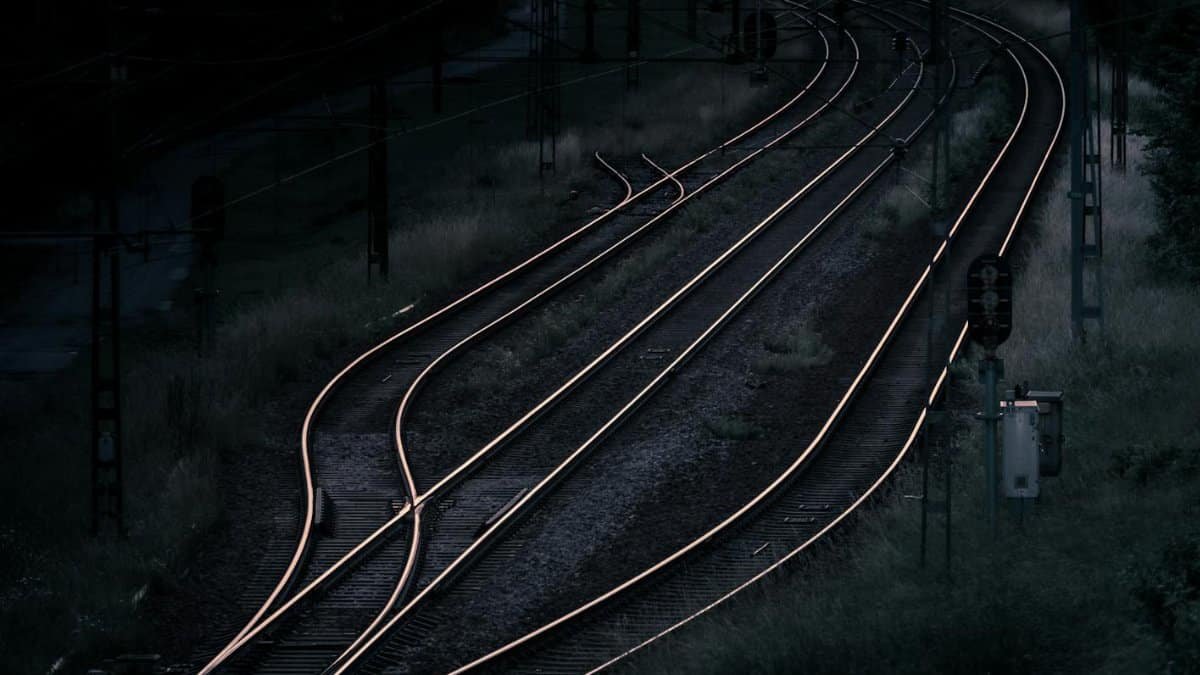 Aerial view of railway tracks at night in a remote, rural area, capturing a dark and moody ambiance.