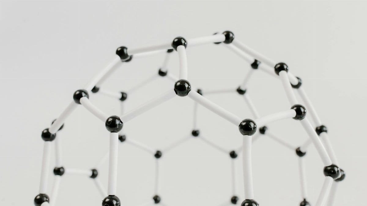 Close-up of a geometric molecular structure model with black and white connections on a light background.