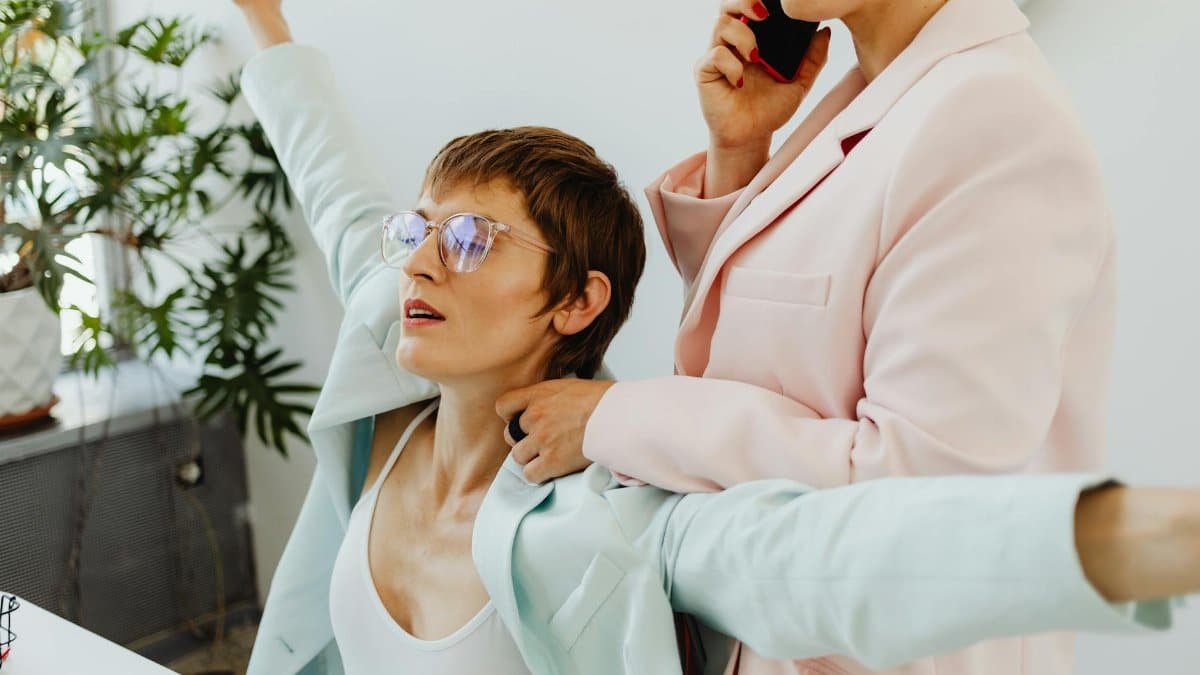 Two women in pastel suits engaging casually indoors. Modern lifestyle concept.