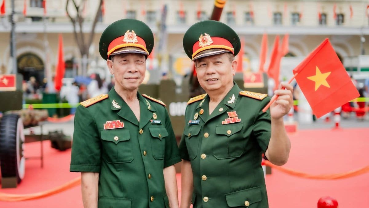 Two senior military officers celebrate a national event by holding a flag outside.