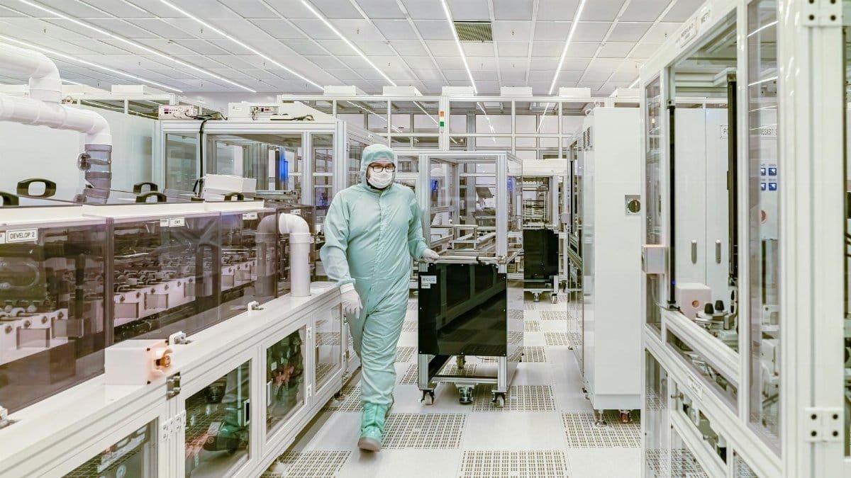 Scientist in protective gear walking in a high-tech cleanroom laboratory environment.