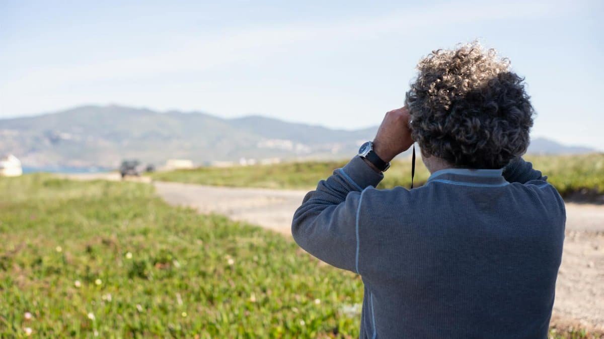 Adult man using binoculars outdoors in Portugal, capturing scenic landscape views.