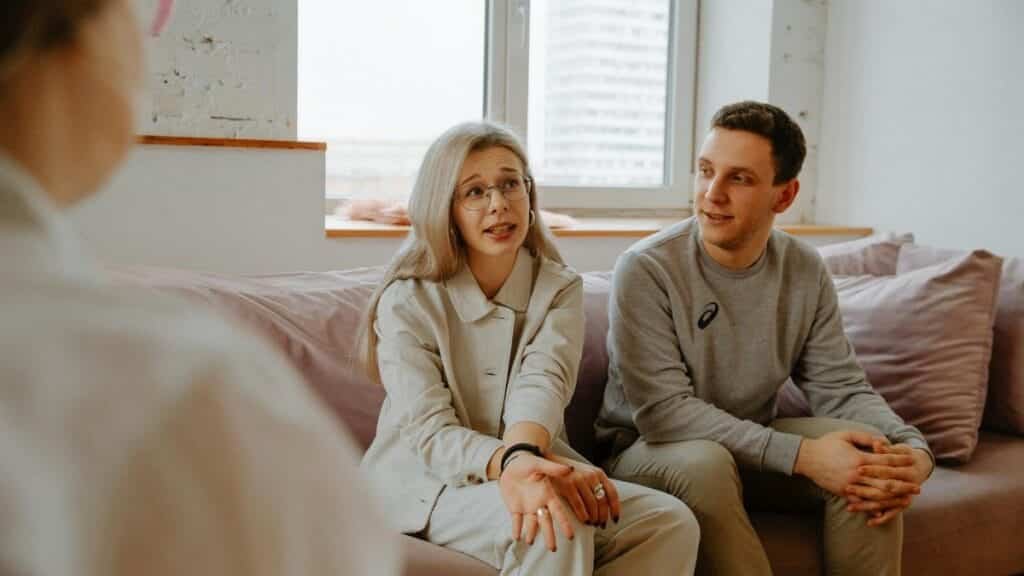 A couple and therapist engaged in a discussion during a therapy session indoors.