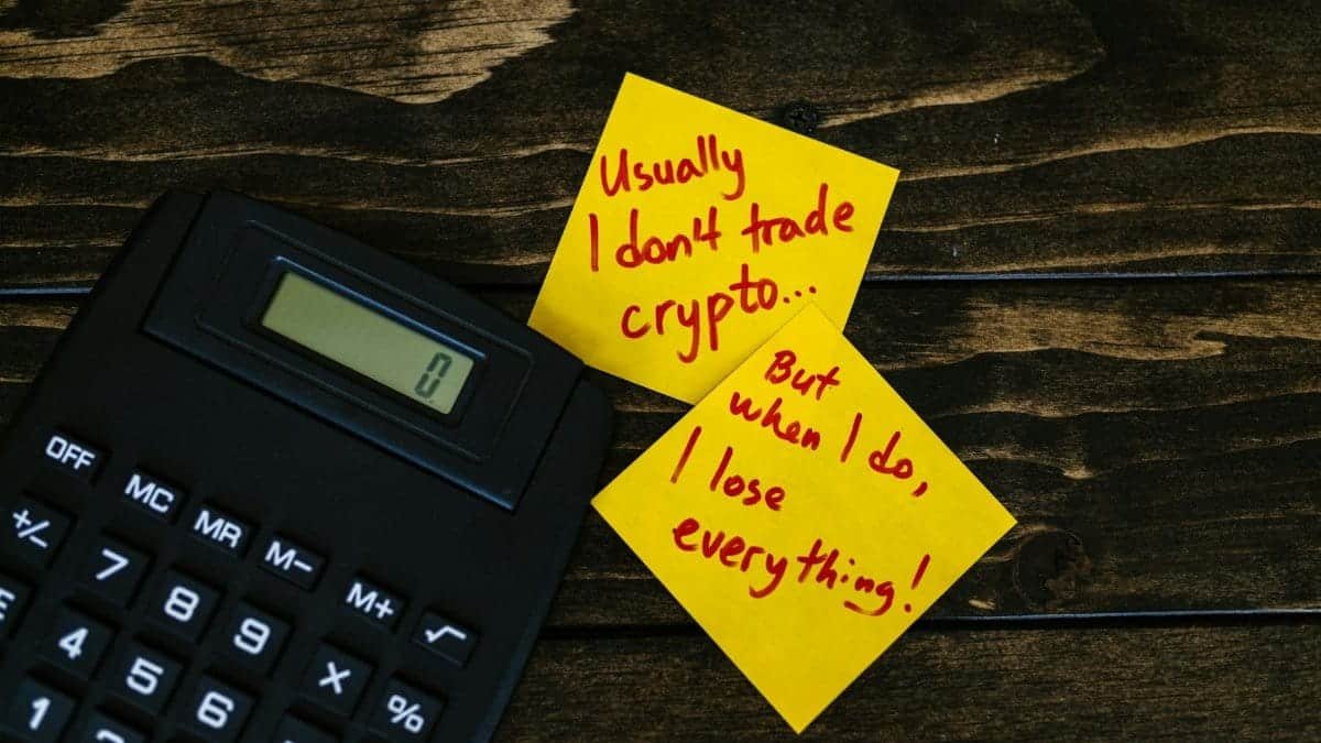 Funny sticky notes about cryptocurrency trading with calculator on wooden table.