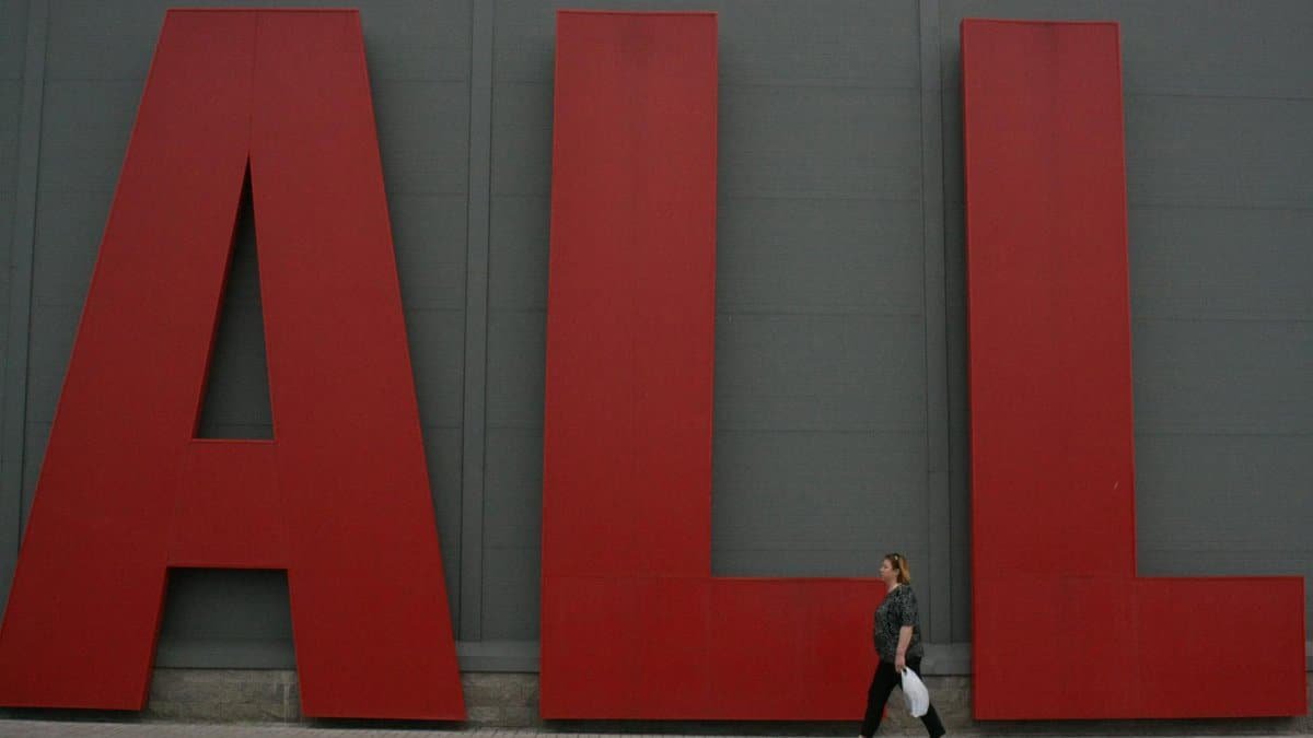 A woman walks past giant red letters spelling 'ALL' in Minsk, Belarus.