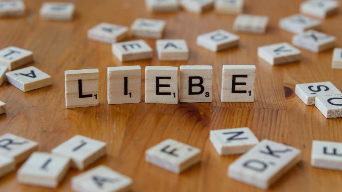 Scrabble tiles spelling 'Liebe' on a wooden table, symbolizing love and language.