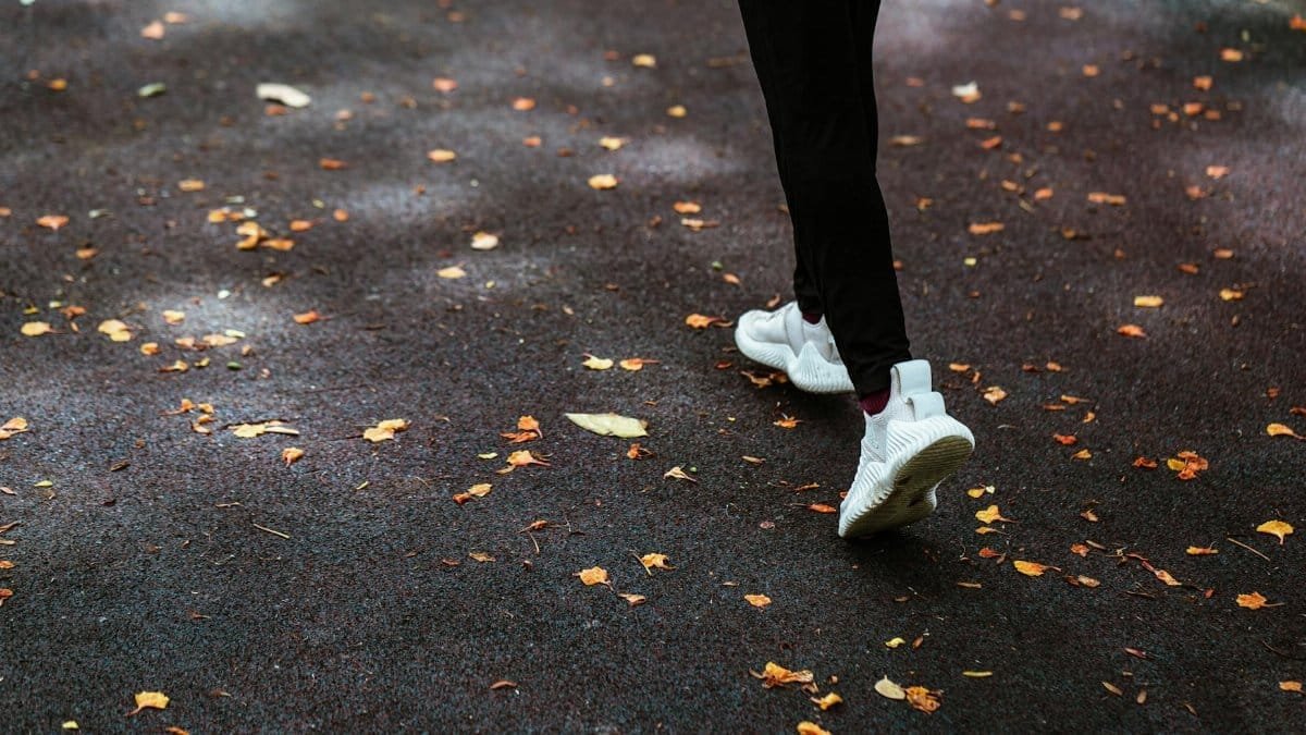 A person running outdoors on a leaf-covered path, showcasing fitness and vitality.