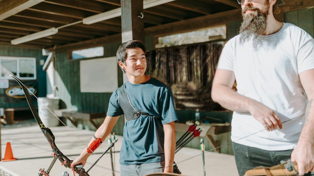 Two men practicing archery outdoors, focusing on technique and form.
