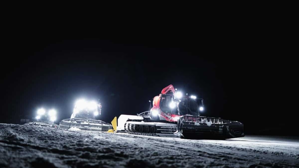 Illuminated snow groomers working at night in Zermatt, Switzerland during winter.