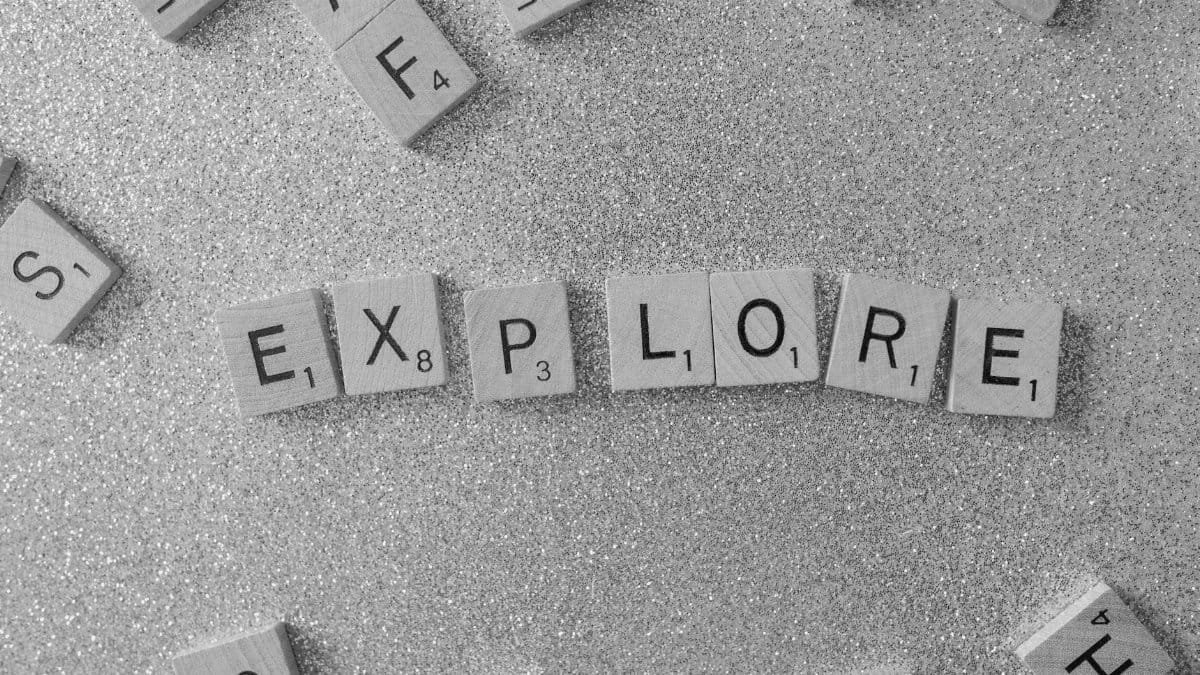 Ambient shot of Scrabble tiles spelling 'Explore' on a glittery surface.