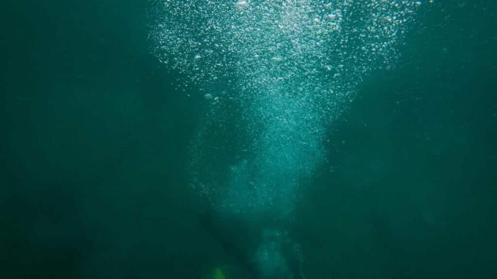 A scuba diver creates a trail of bubbles while exploring the deep ocean underwater.