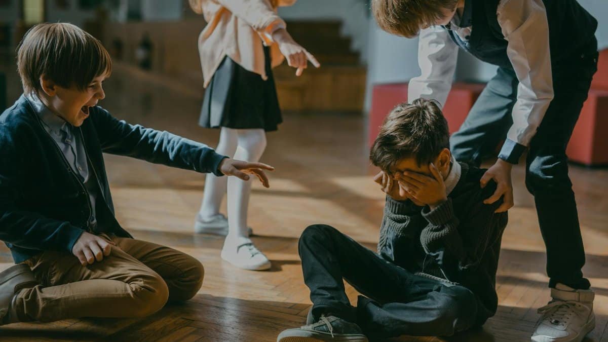 Group of kids bullying another child at school, signaling peer pressure and harassment.