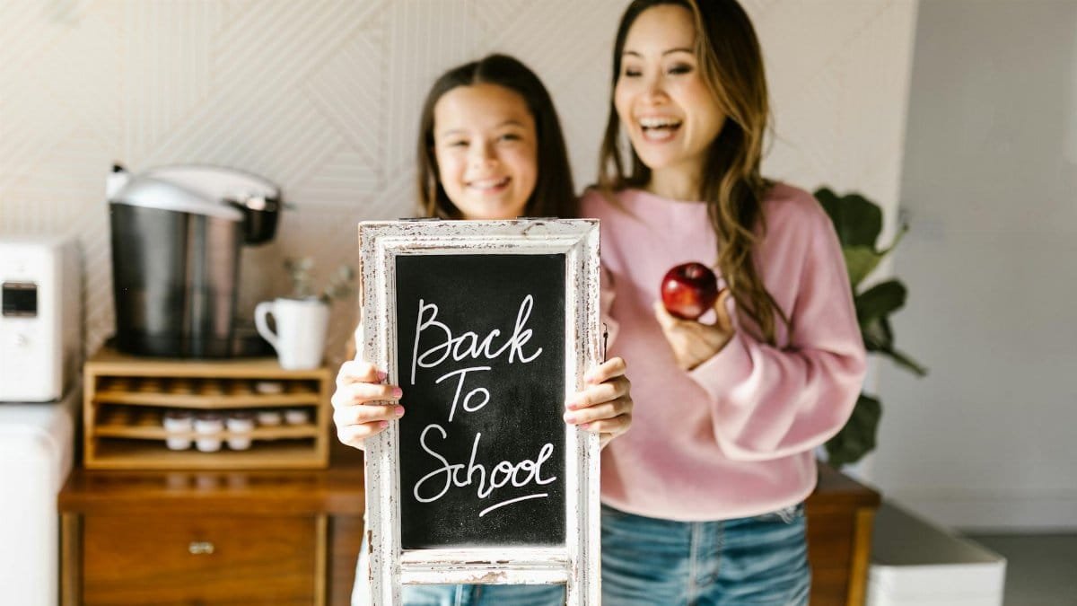Happy mother and daughter enjoying back to school moment indoors.