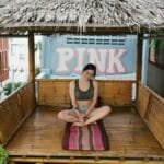 A woman practices meditation in a bamboo hut on a rooftop, promoting relaxation amidst urban settings.