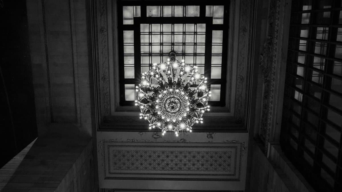 A black and white view of an ornate chandelier from below in Grand Central Terminal.