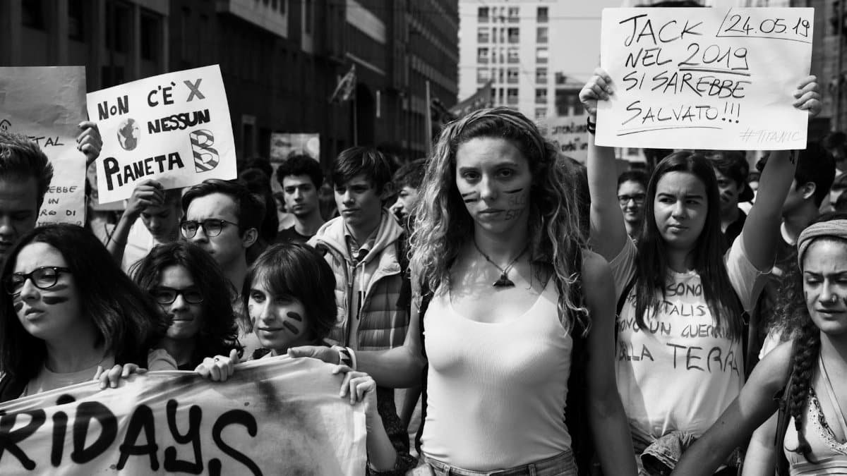 Activists march in Milan for climate change awareness, holding signs for environmental action.