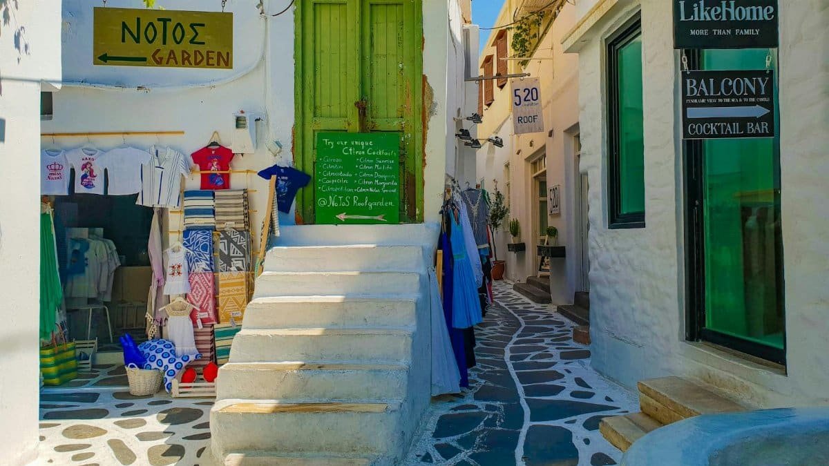 Picturesque alley in a Greek village showcasing local shops and vibrant architecture.