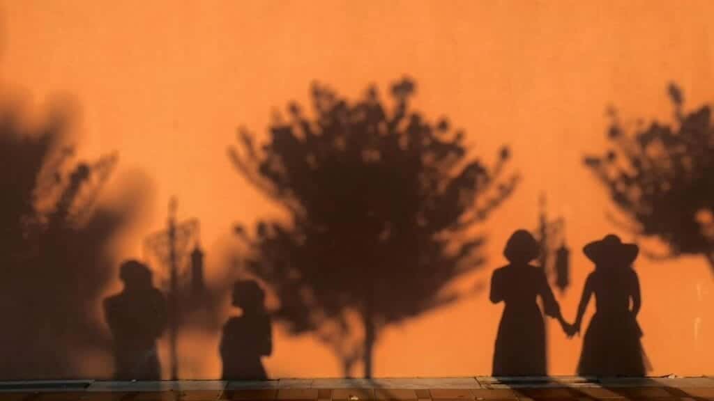 Shadows of people and trees on a sunlit wall create a striking scene in İstanbul.