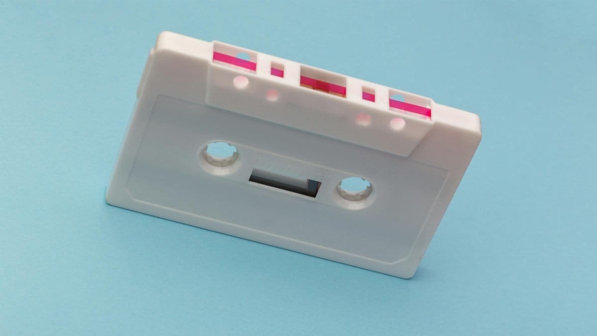 Vintage white cassette tape against a vibrant blue backdrop, capturing classic audio technology nostalgia.