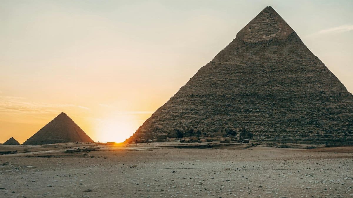 Dramatic sunset view of the iconic Giza Pyramids in Egypt, highlighting their ancient architecture.